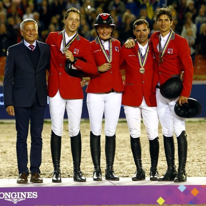 Photo quatre cavaliers avec veste rouge et une médaille sur un podium