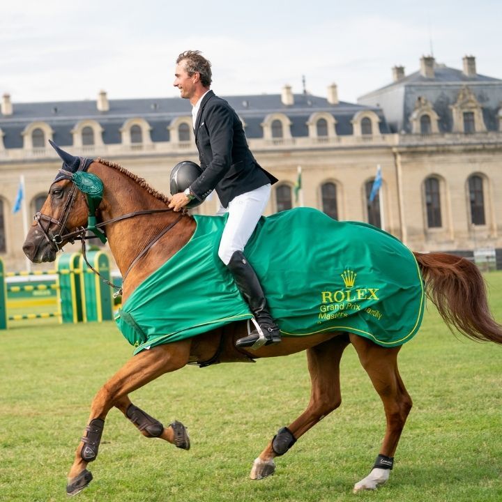 Cavalier sur cheval marron avec une couverture verte