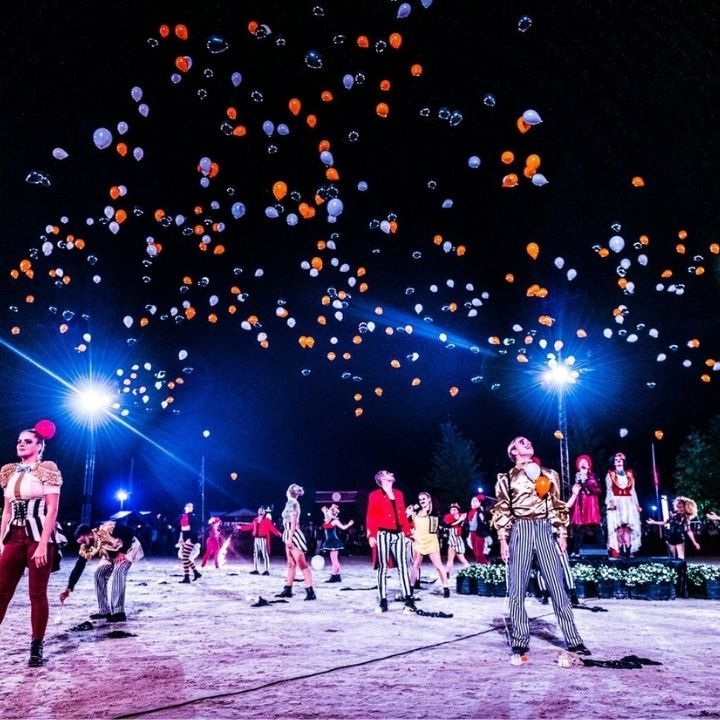 Ballons gonflables blanc et orange qui s'envolent et un groupe de personne en dessous
