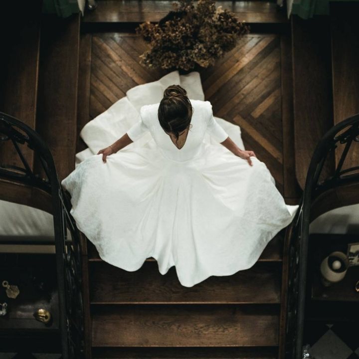 Fille dans une robe de mariage blanche sur des escaliers en bois