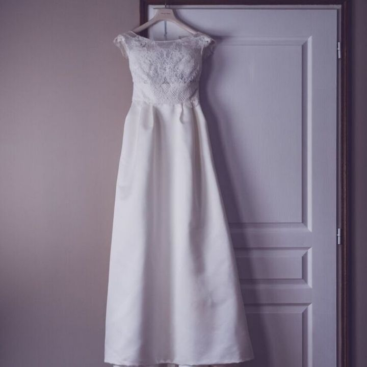 Photo d'une robe de mariage blanche accrochée à une porte blanche