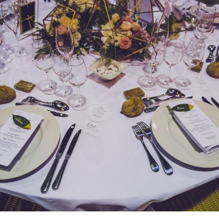 Photo d'une table blanche avec des assiettes couverts et verres